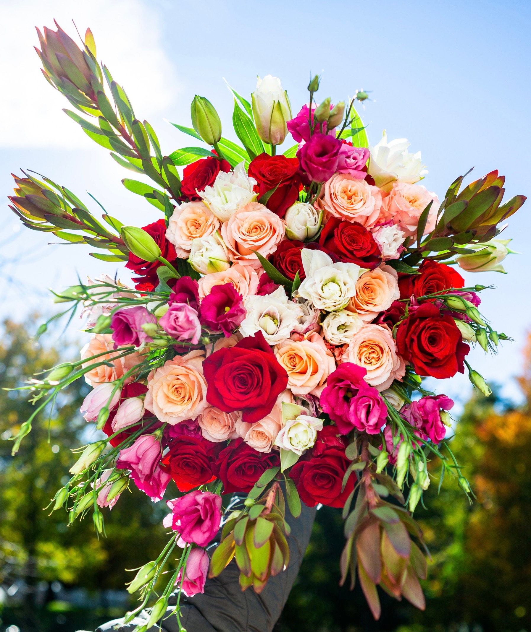 Poetic — handcrafted hand-tied bouquet with red and peach roses, white and magenta lisianthus, and leucadendron, Livingston NJ florist